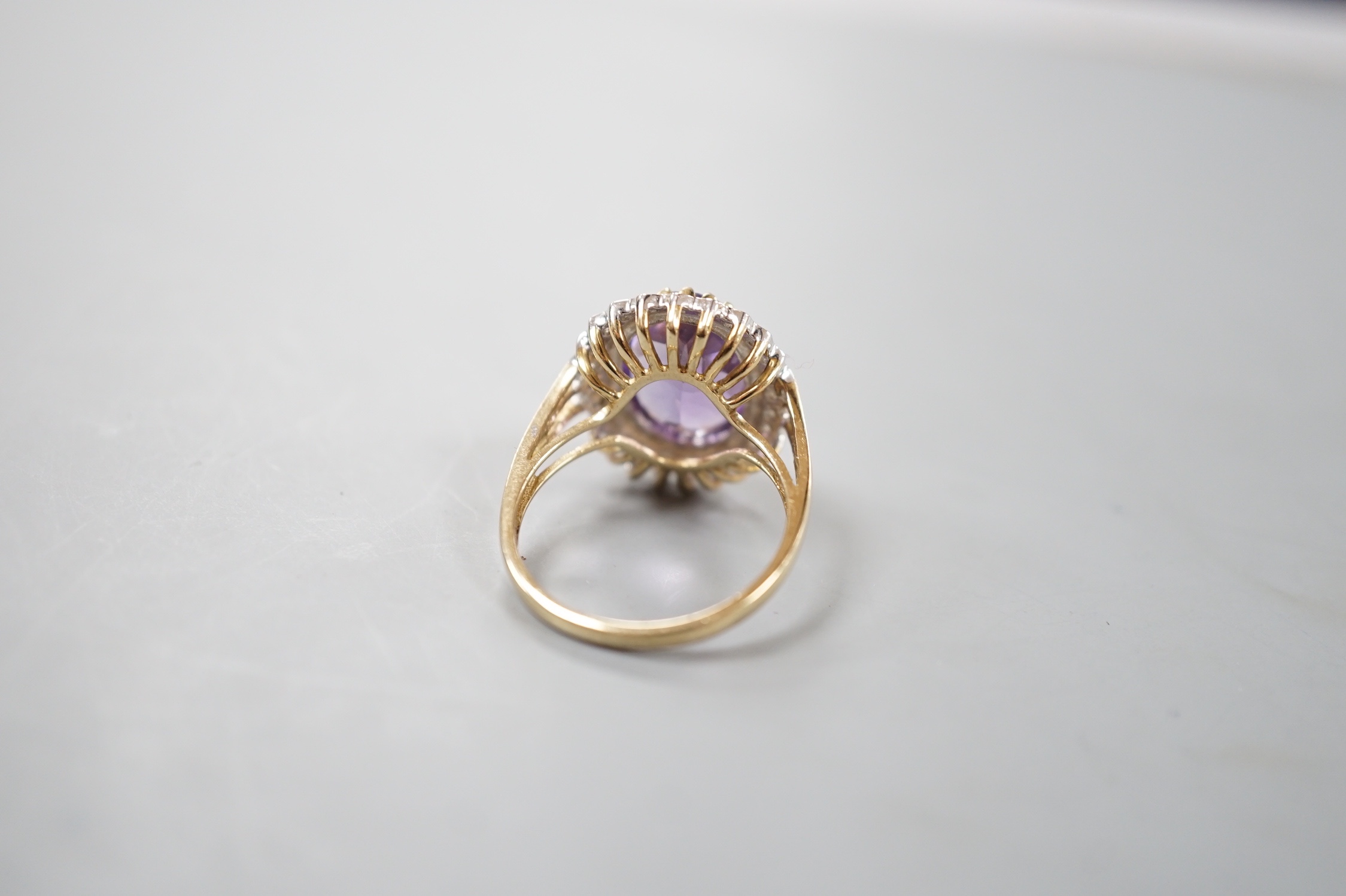 A modern 9ct gold, amethyst and diamond chip set oval cluster ring, size Q, gross weight 4.6 grams.